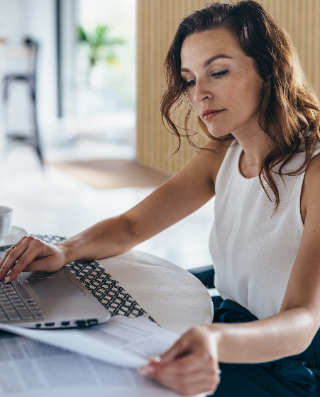 Person working at a laptop looking at a piece of paper