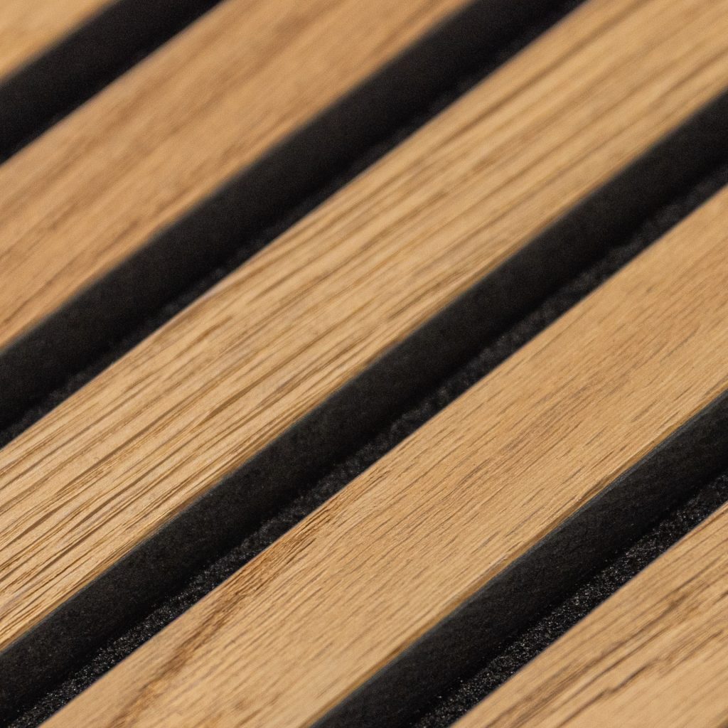 Nærbillede af WoodUpp trælister: lyse egetræslameller med tydelig årestruktur og fint slebet, lagt parallelt og adskilt af smalle sorte gummilister. Billedet fremhæver overfladedetaljer, naturlige farvevariationer og kontrasten mellem varm trætekstur og mørke mellemrum, typisk for WoodUpp’s lamel-design.
